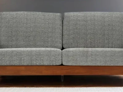 Wooden sofa with three cushions and neutral colored fabric upholstery